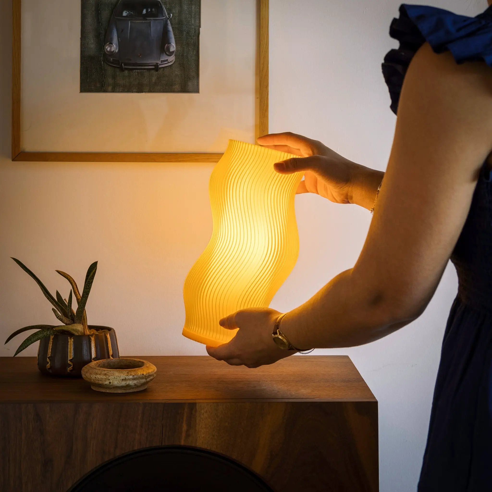 Woogie Table Lamp with a warm yellow ribbed shade on a wooden table.