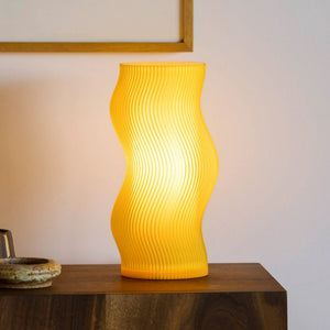 Woogie table lamp by Terra Labs with a bright yellow ribbed body on a wooden table