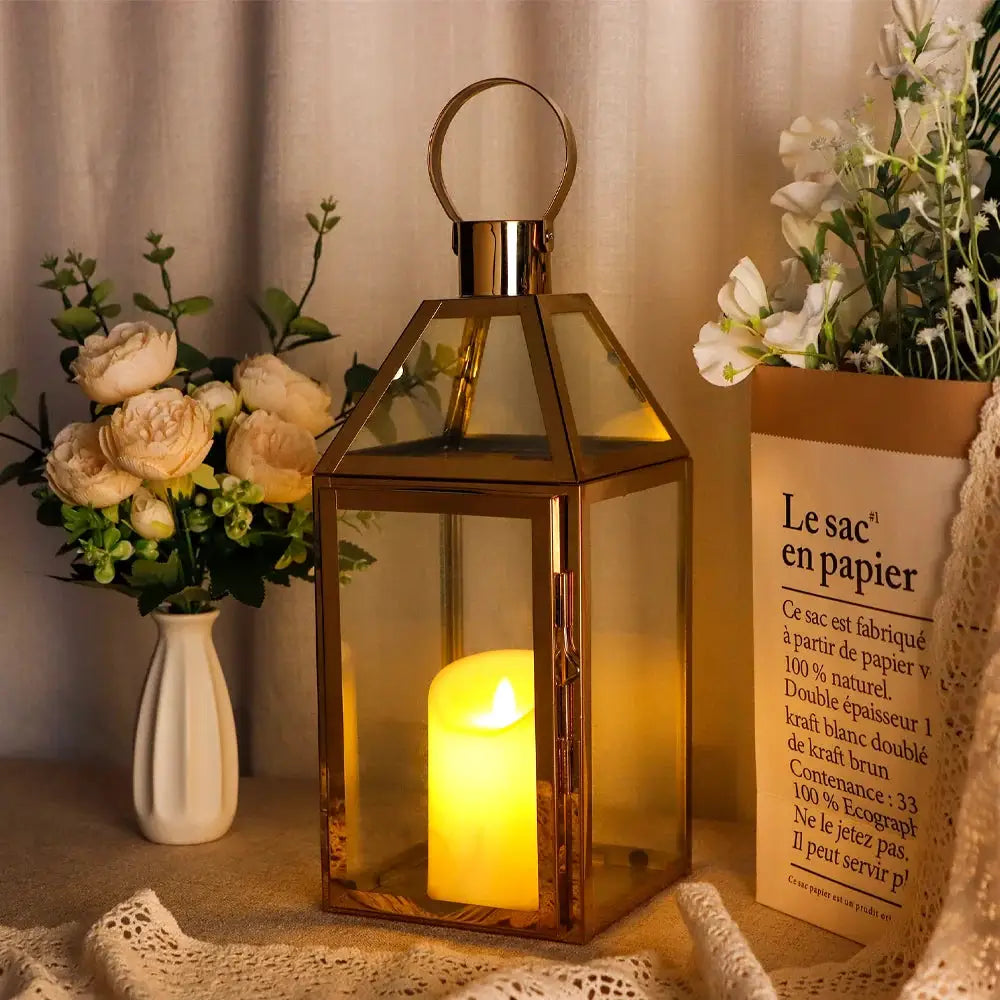 Gold 16in stainless steel decorative candle lantern with glass panels and a lit candle inside