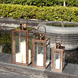 Set of 3 rose-gold stainless steel decorative candle lanterns with glass panels and curved handles