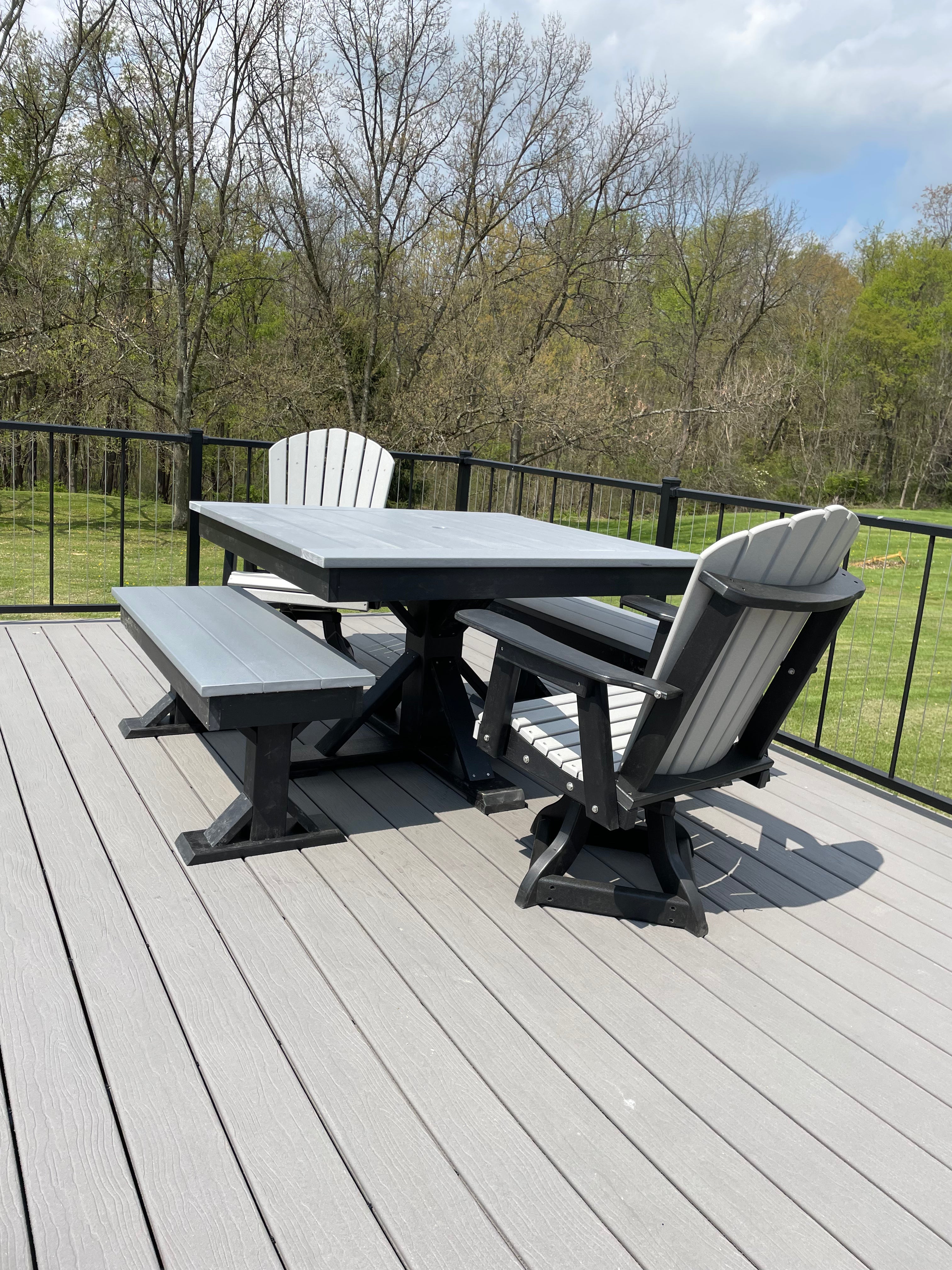 Trestle X Outdoor Square Dining Table with gray top and black base, on a deck with two gray chairs and a matching bench.