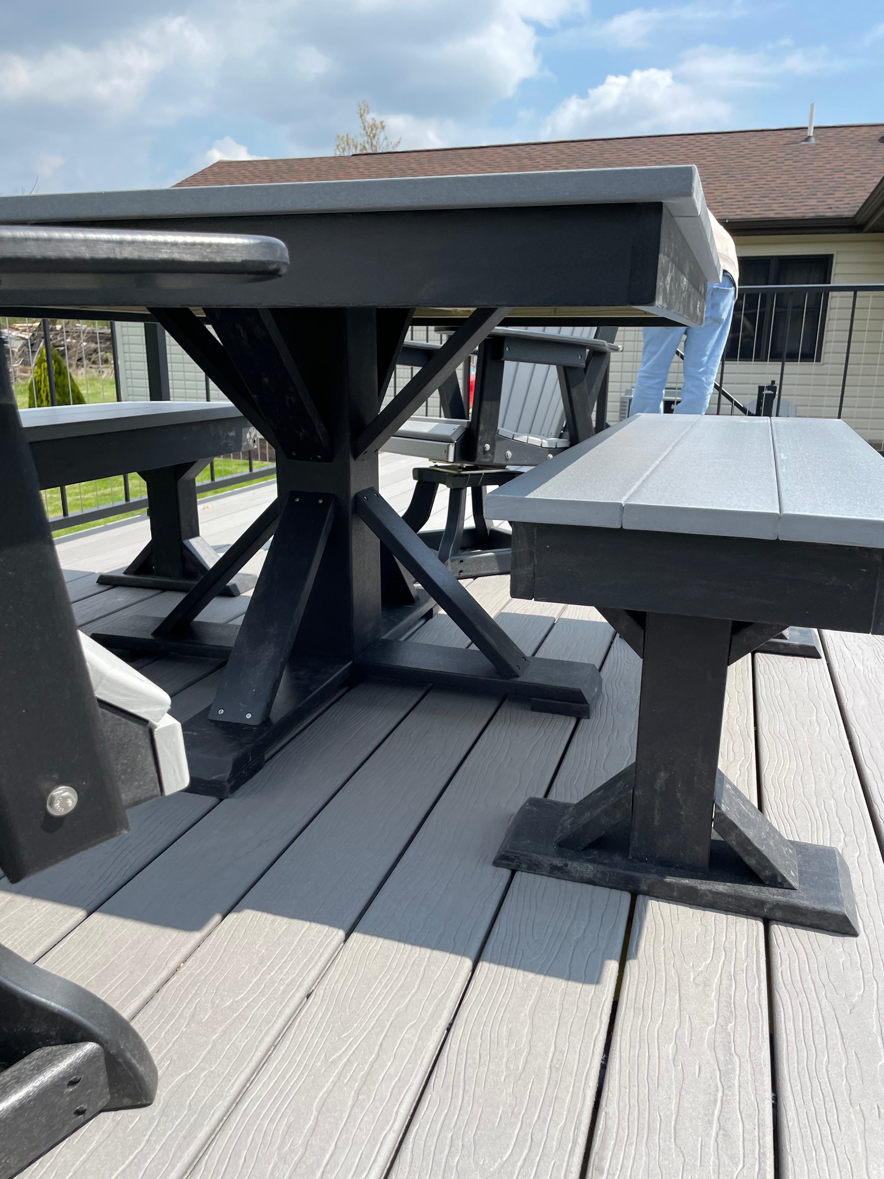 Trestle X Outdoor Square Dining Table by Wooden Whale Workshop; dark frame with gray top on a deck