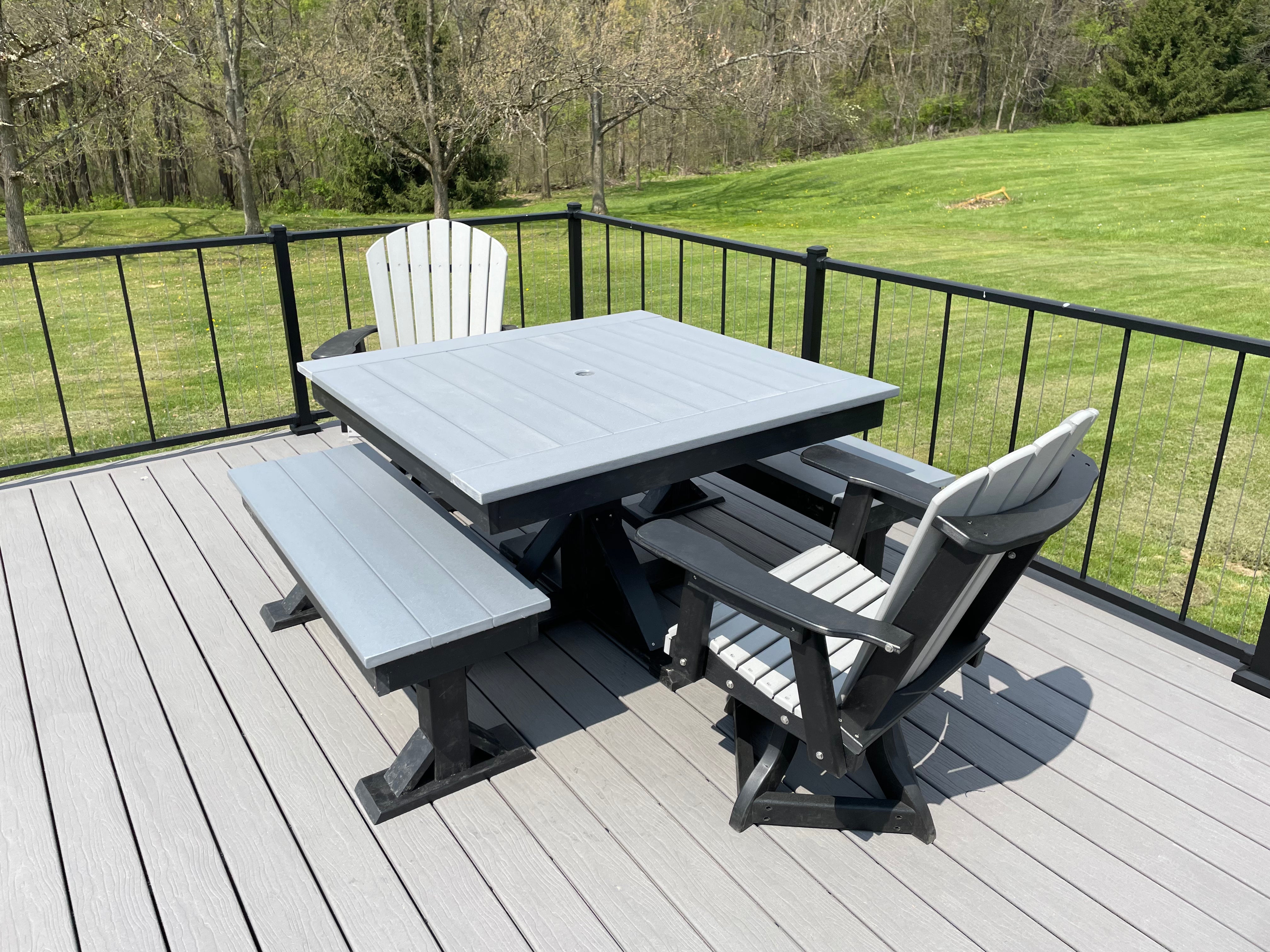 Trestle X Outdoor Square Dining Table with blue-gray top and black trestle base on a deck, surrounded by chairs.