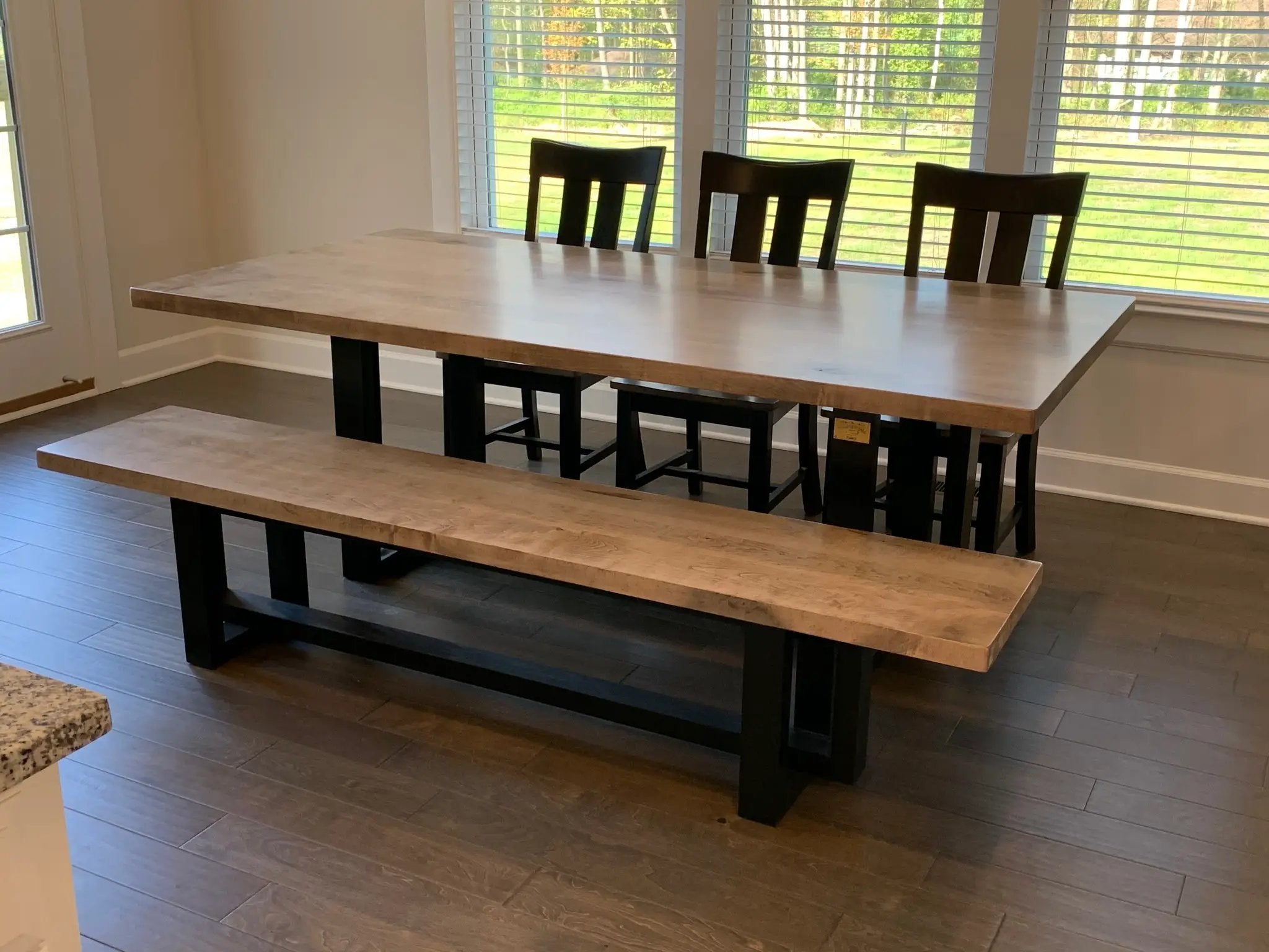 Heston dining table by Wooden Whale Workshop, light wood top with black legs, shown with benches and chairs.