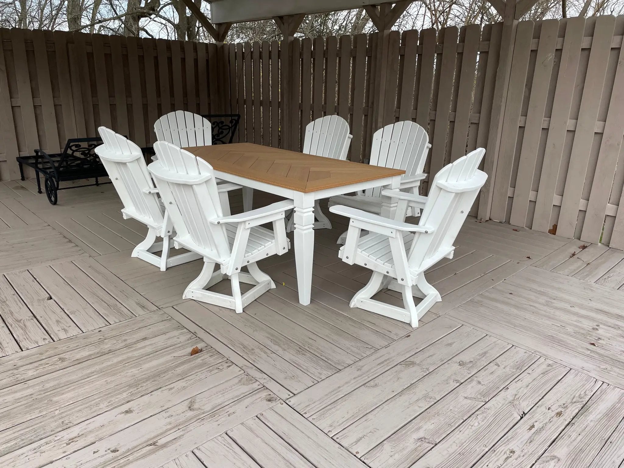 Java Leg Outdoor Dining Table with natural wood top and white base, surrounded by white Adirondack chairs on deck