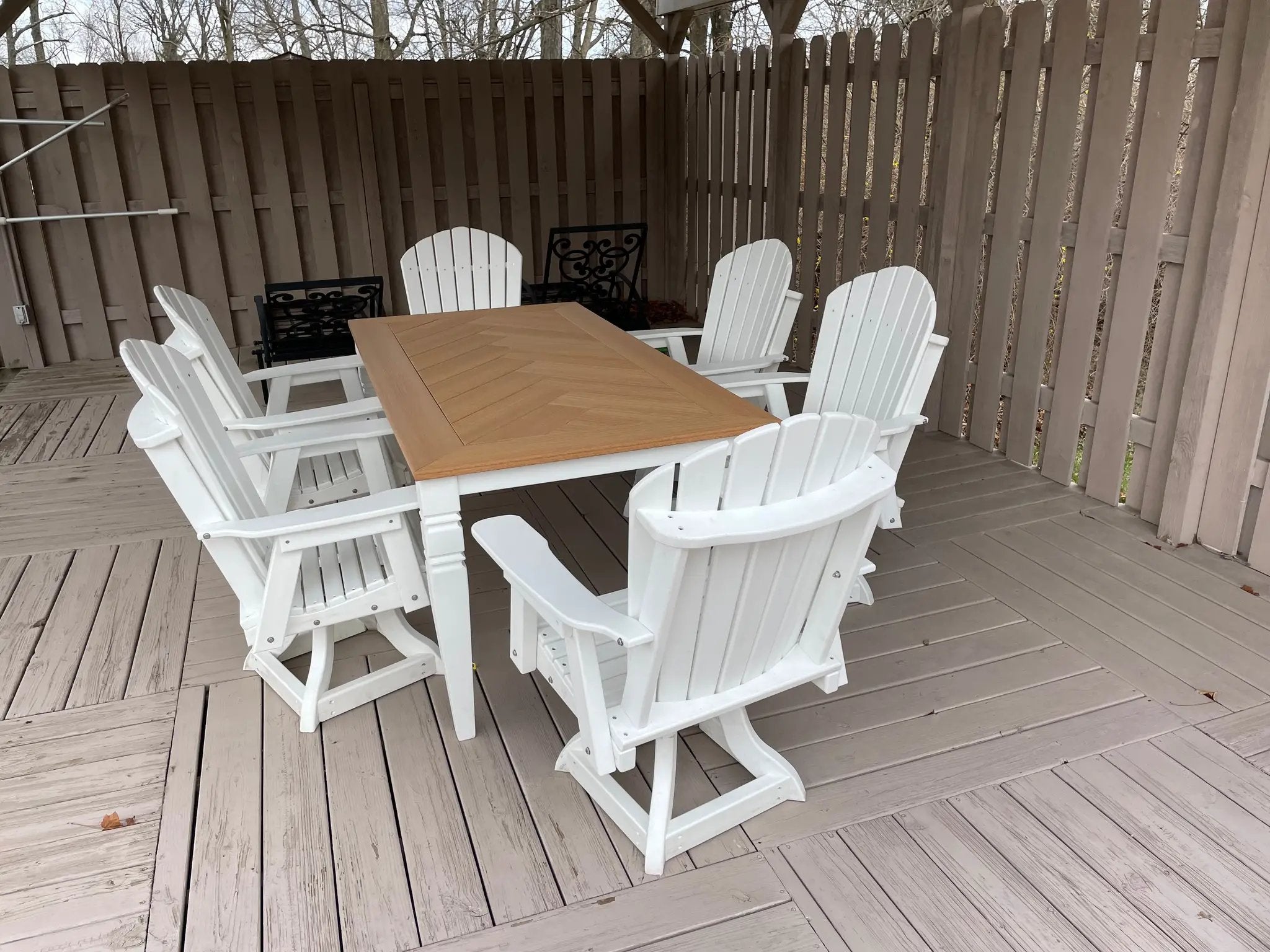 Java Leg Outdoor Dining Table with a natural wood top surrounded by white Adirondack chairs on a deck.
