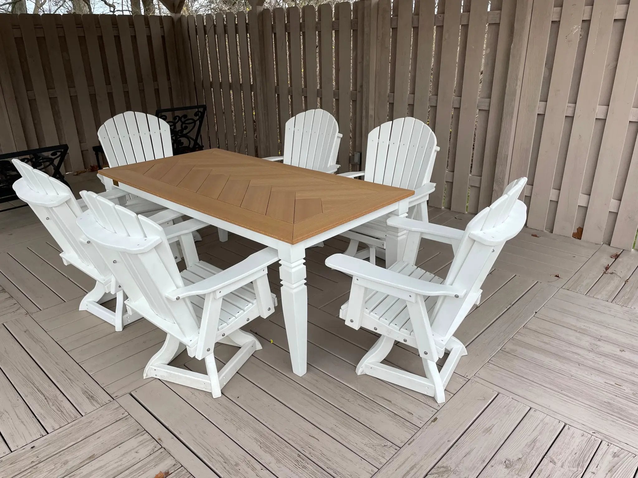 Java Leg outdoor dining table with a natural wood top and white base, surrounded by white Adirondack chairs on a deck