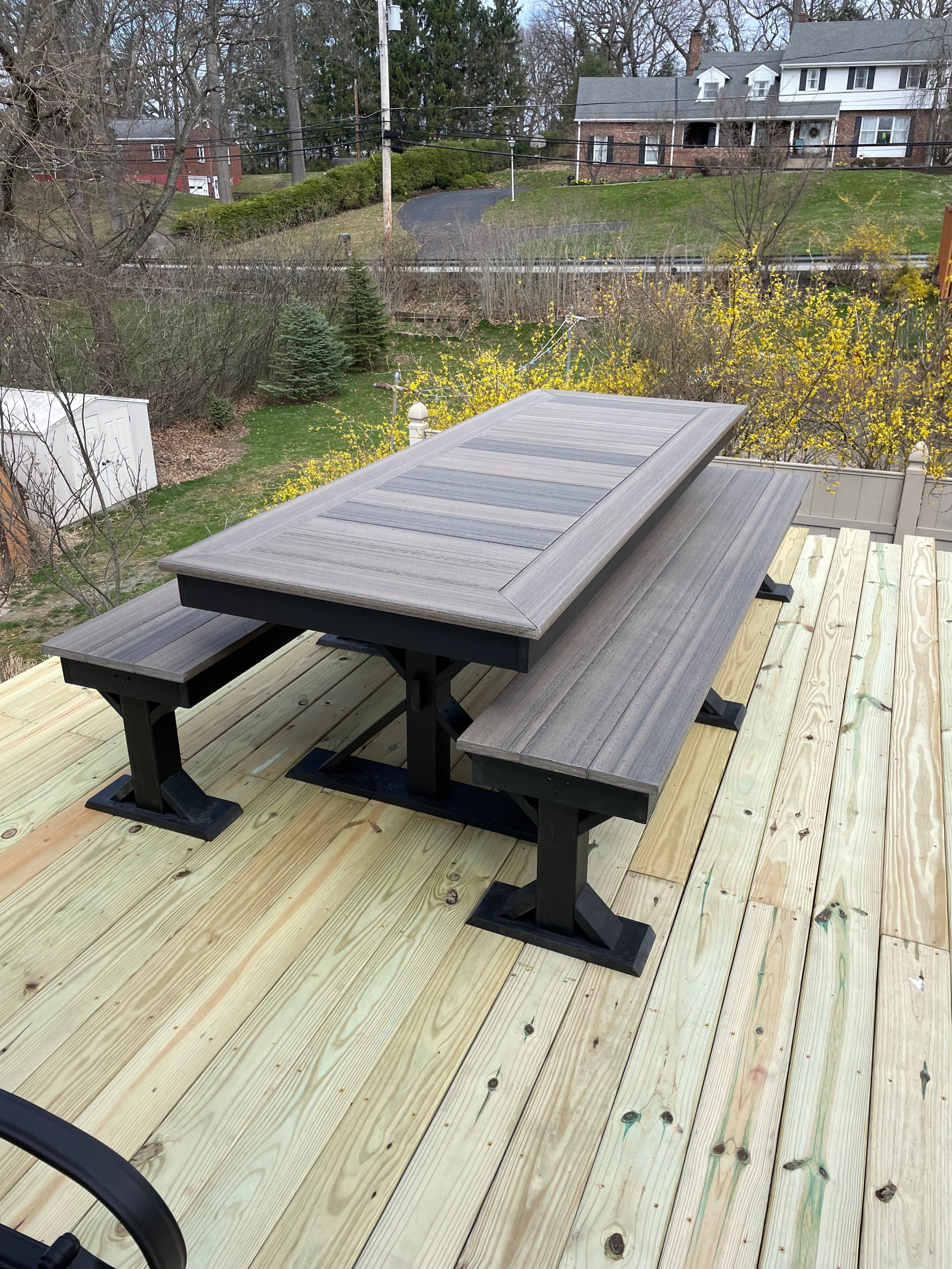 Trestle X Outdoor Bench by Wooden Whale Workshop; gray-stained wood with trestle legs on a deck.