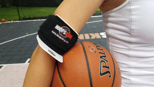 Bulls Eye Basketball Shooting Aid by HoopsKing on a black wrist strap with white trim beside an orange basketball.