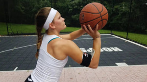 HoopsKing Bulls Eye Basketball Shooting Aid on forearm, white plastic brace used during outdoor court shooting practice