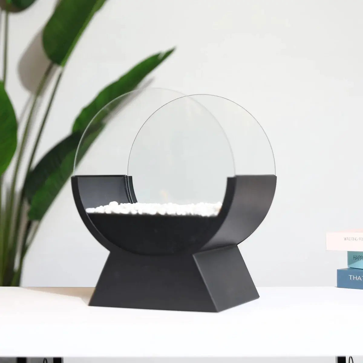 13.5-inch tall tabletop fireplace in black with a round glass guard, white decorative pebbles, and a small flame