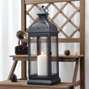 19-inch high rustic black metal candle lantern with glass panels and ornate filigree, candle inside
