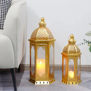 Set of 2 gold-tone metal candle lanterns with lattice dome tops and glass panels, candles lit.
