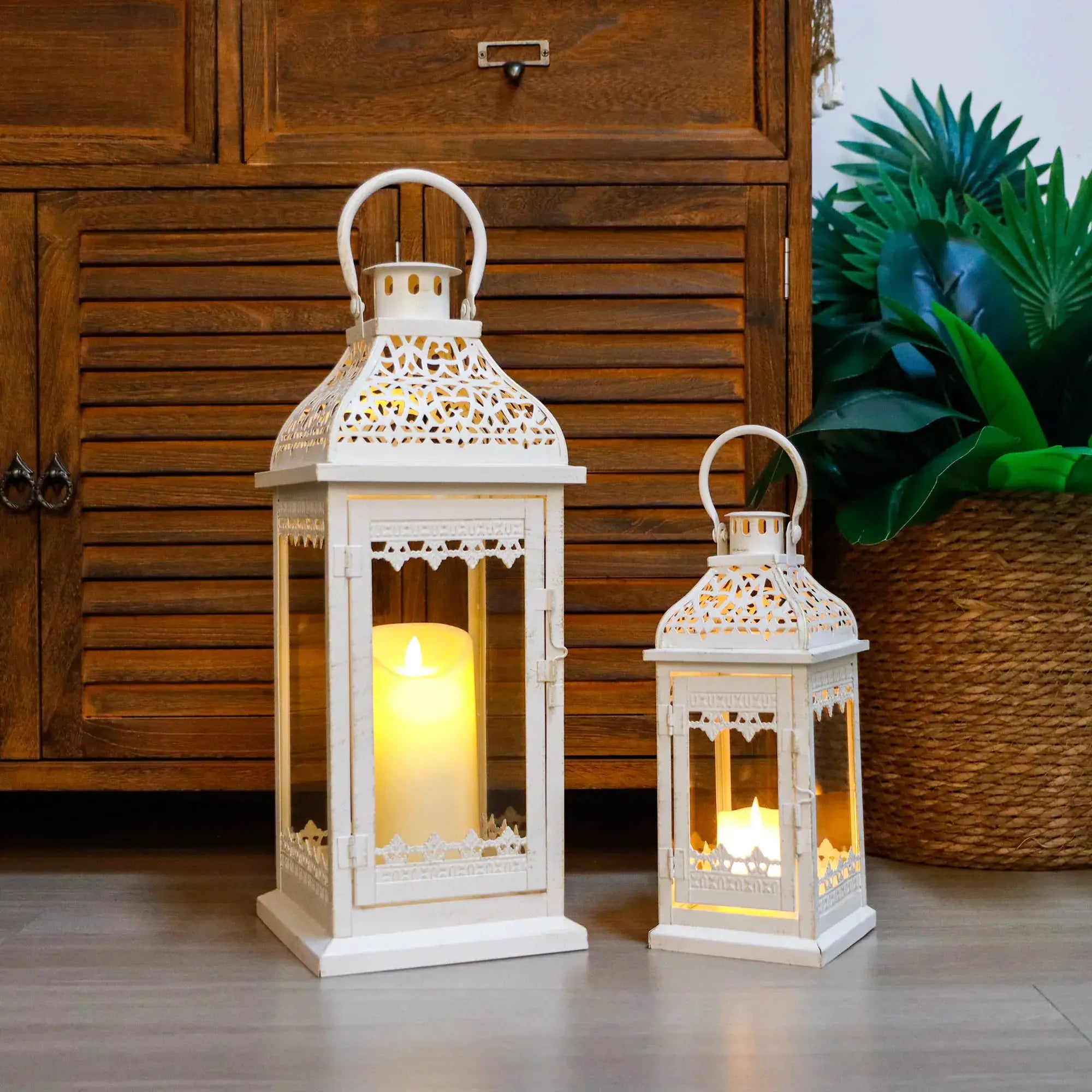 Set of 2 decorative metal candle lanterns in white/beige with ornate lattice panels, lit from within.
