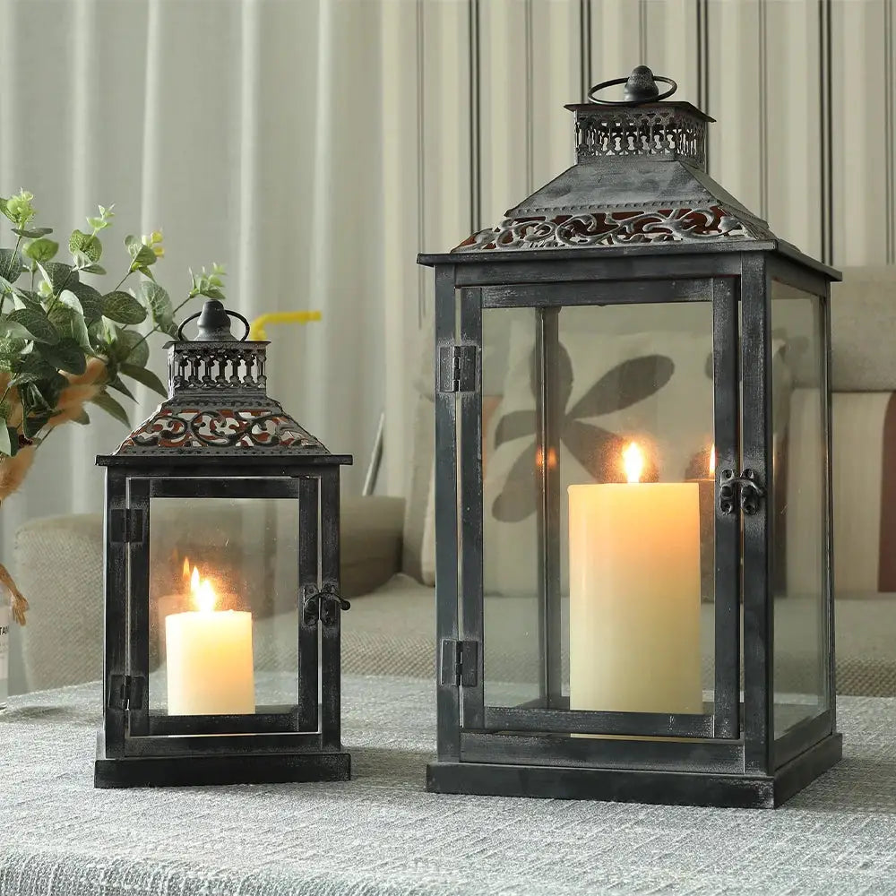 Set of 2 antique grey brush decorative candle lanterns with glass panels, ornate vented tops, and lit candles.