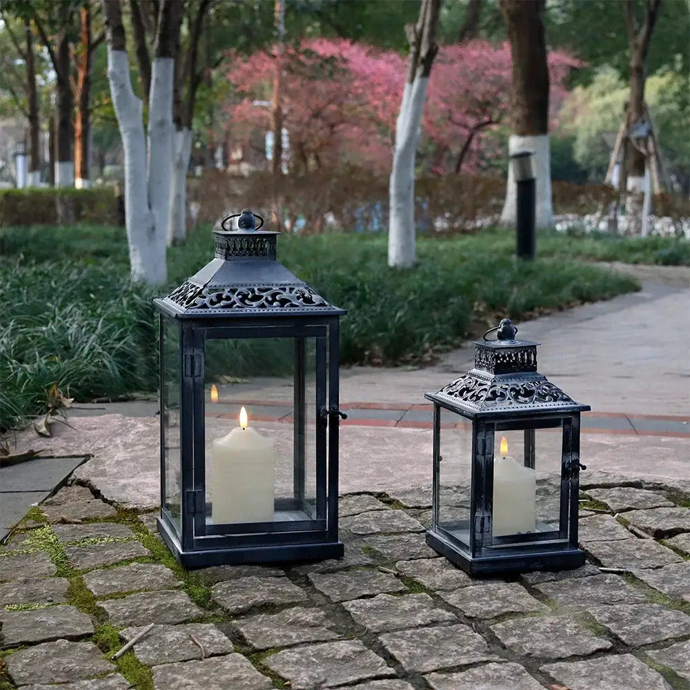 Antique grey brush decorative lanterns, metal frames with glass panes and lit candles inside, set of 2