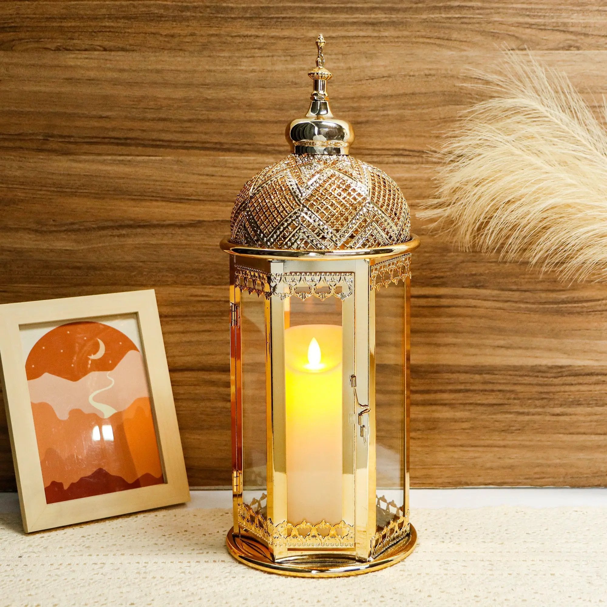 Moroccan candle lantern, gold, 15-inch hexagonal metal frame with glass panels and a lit candle inside.