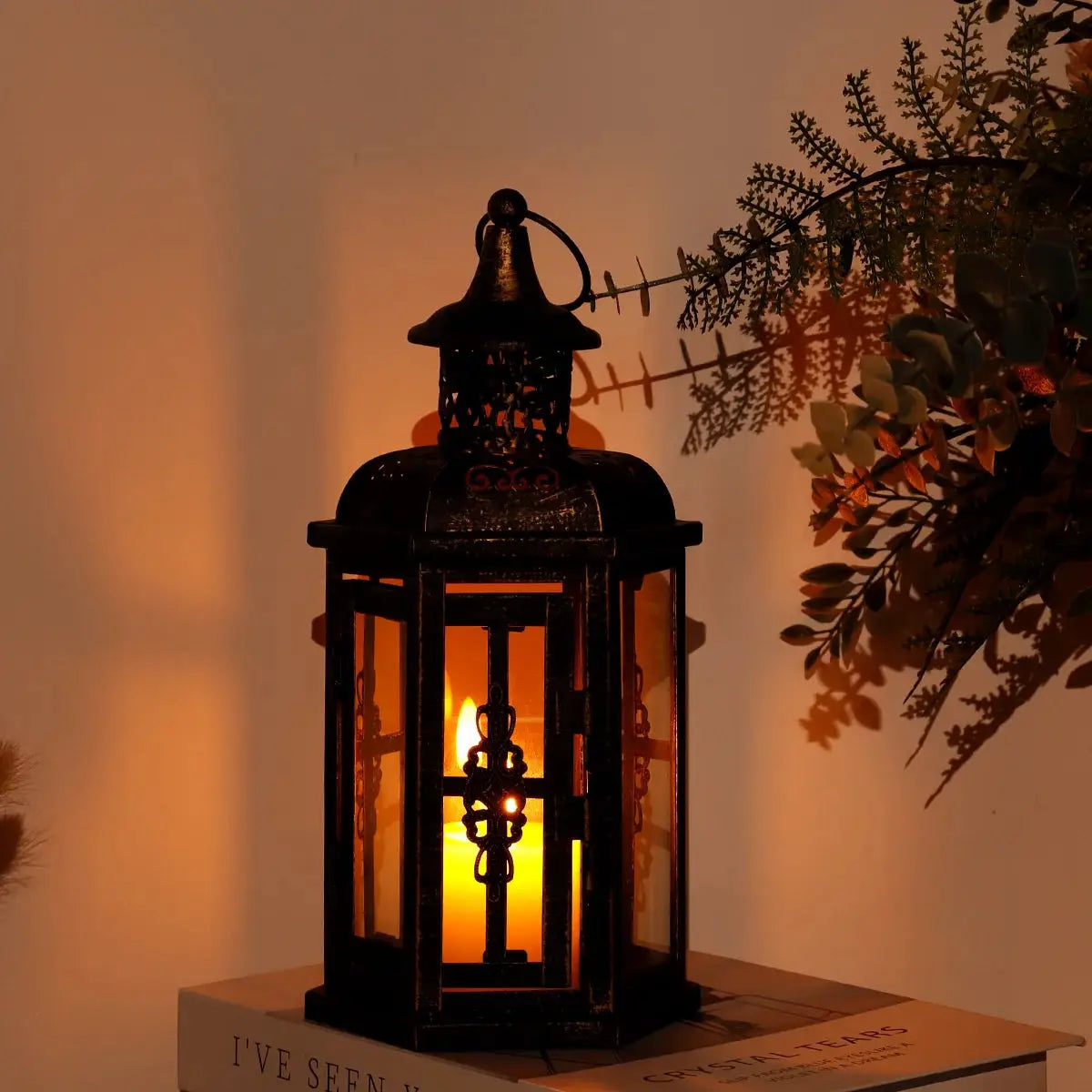 12-inch metal candle lantern in black with gold brush finish, candle glowing inside