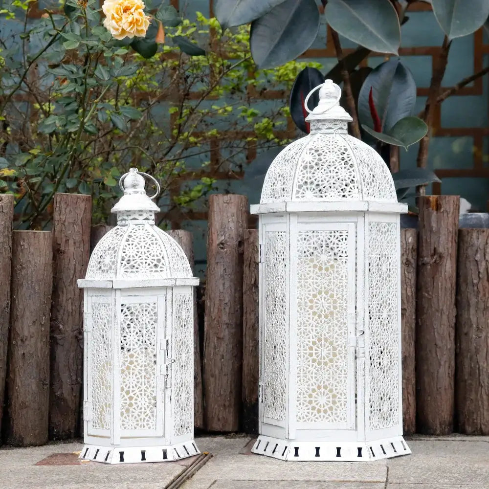 Set of 2 white metal lanterns by JHY DESIGN with intricate lattice and vintage domed tops; heights 15 and 19.5 inches.