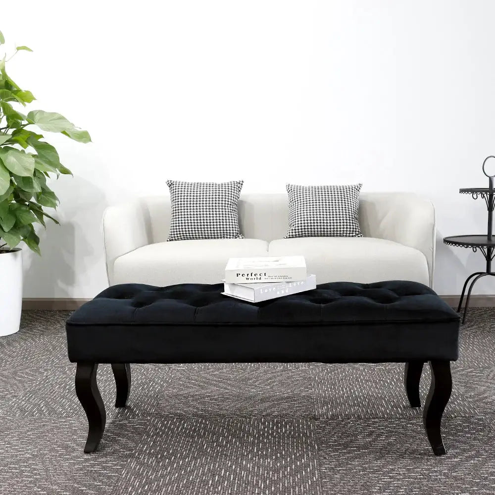 Black Dutch velvet ottoman bench with tufted top and curved legs.