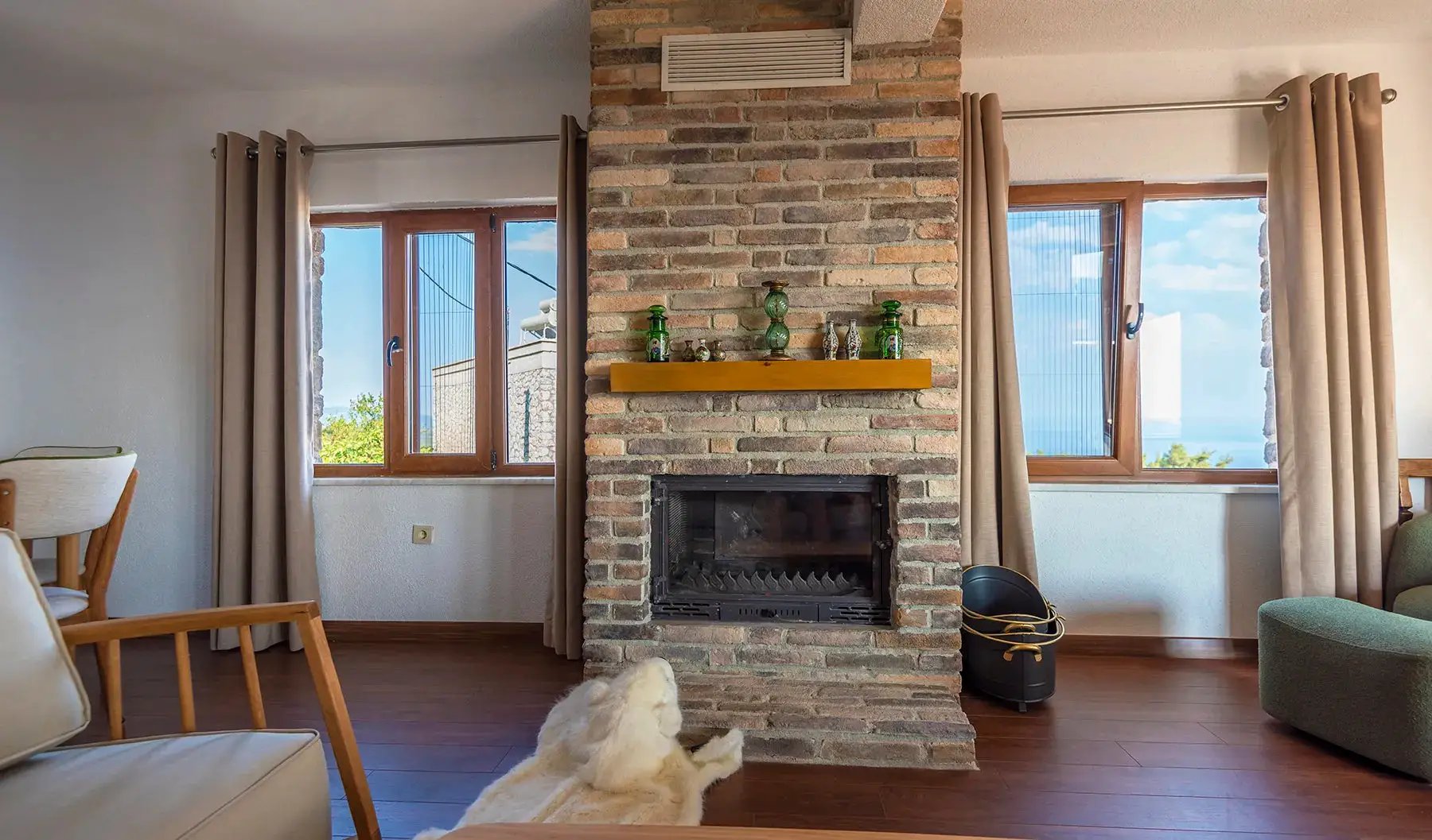 Ferrara Old School brick veneer fireplace in a living room with wooden floors and large windows.