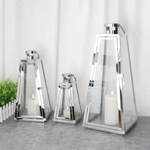 Set of 3 stainless steel candle lanterns with glass panels and candles inside in varying heights