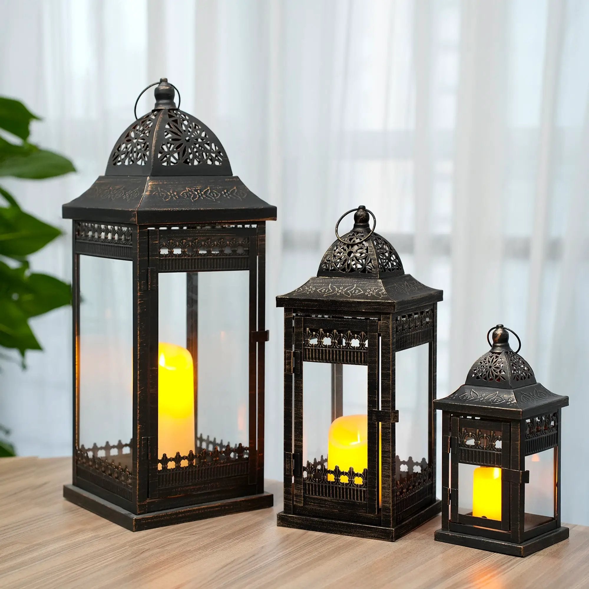 Decorative candle lanterns set of 3 in black metal with intricate lattice panels and warm candlelight