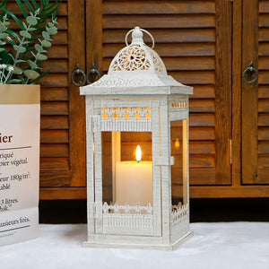 Decorative candle lantern, white distressed metal with intricate lattice dome and glowing candle inside.