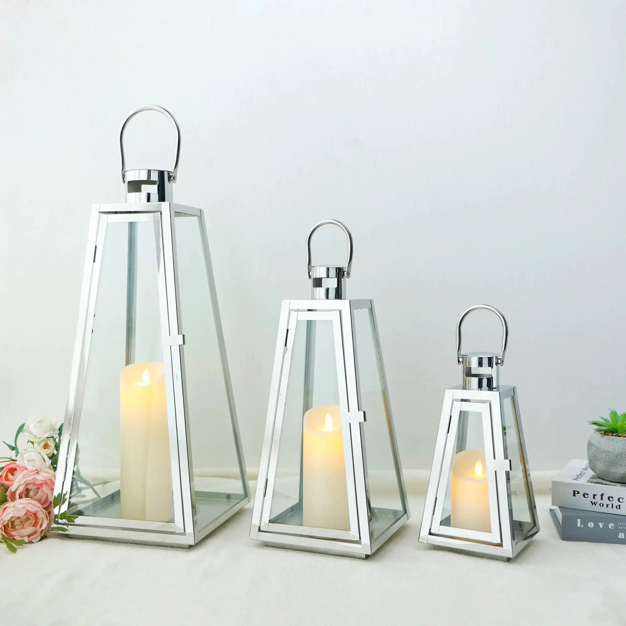 Set of three stainless steel decorative candle lanterns with glass panels in 21in, 16in, and 11in heights.