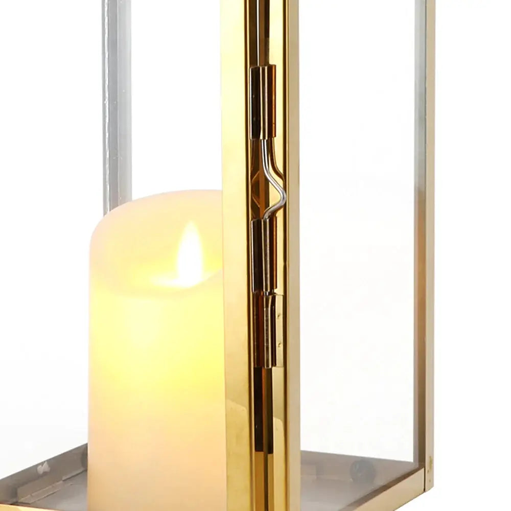 16-inch gold stainless steel decorative candle lantern with glass panels and a lit candle.