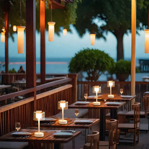 11-inch H 3-way dimmable rechargeable table lamps set with glass cube shades on wooden outdoor dining tables.