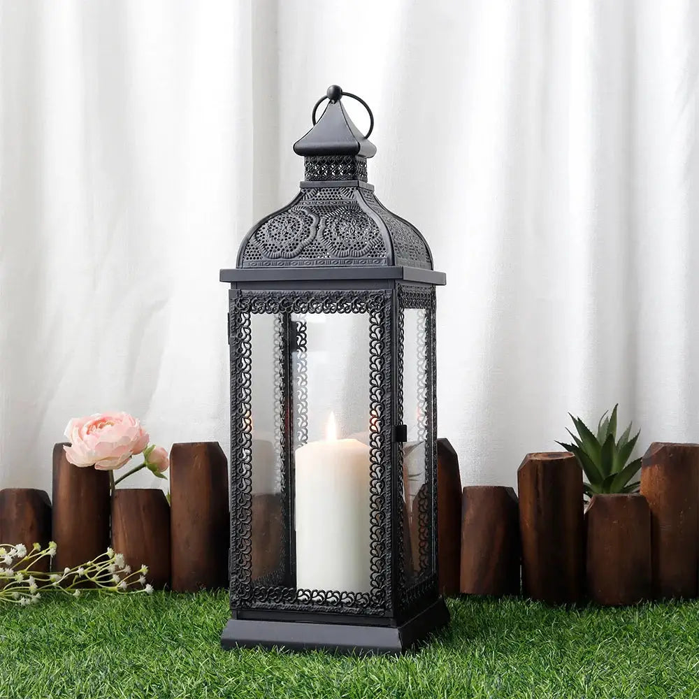 19-inch high rustic black metal candle lantern with glass panels and a white candle.