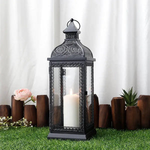 19-inch high rustic black metal candle lantern with glass panels and a white candle.