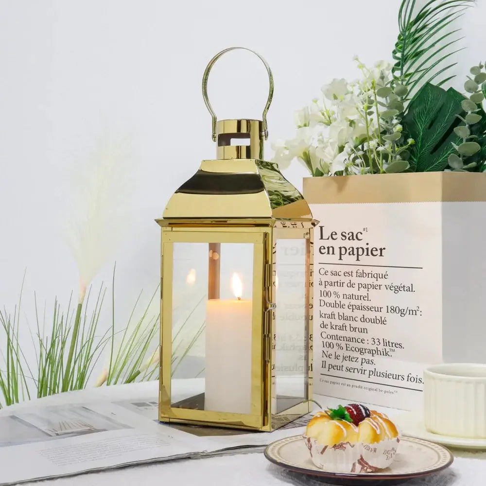 12.5-inch gold stainless steel decorative candle lantern with glass panels and top handle.