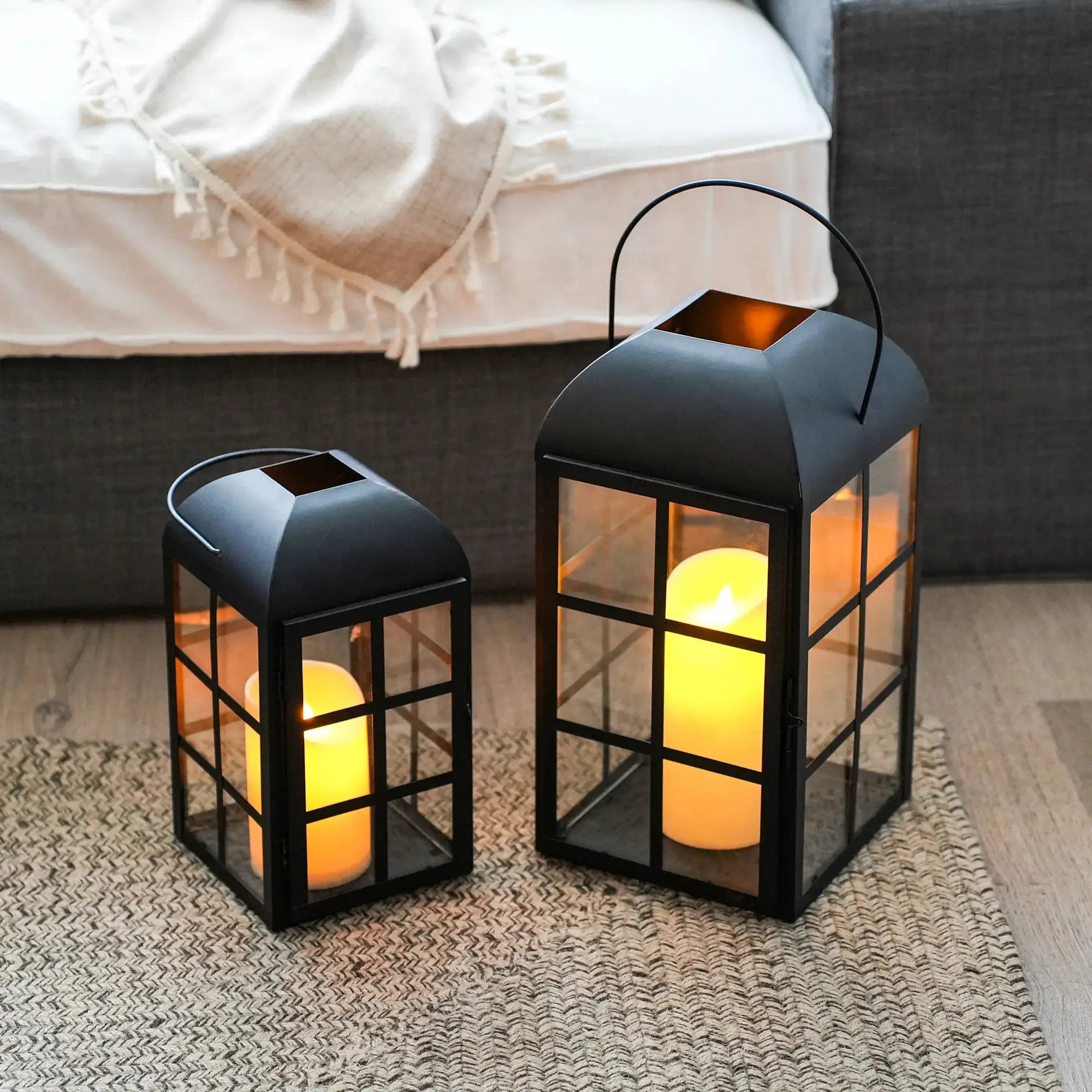 Set of 2 JHY DESIGN decorative candle lanterns, black metal with glass panels and arched handles, containing candles.