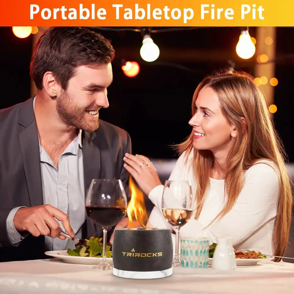 Black graphite color cement concrete portable tabletop fireplace by TRIROCKS on a dinner table with wine glasses.