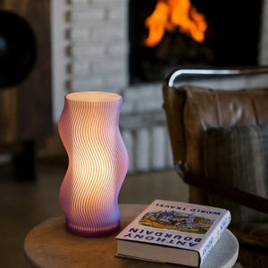 Woogie Table Lamp by Terra Labs; gradient pink-purple sculptural lamp on a round table beside a book.