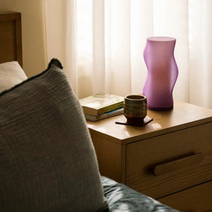 Woogie Table Lamp by Terra Labs; pink ribbed glass with curvy silhouette on a wooden nightstand