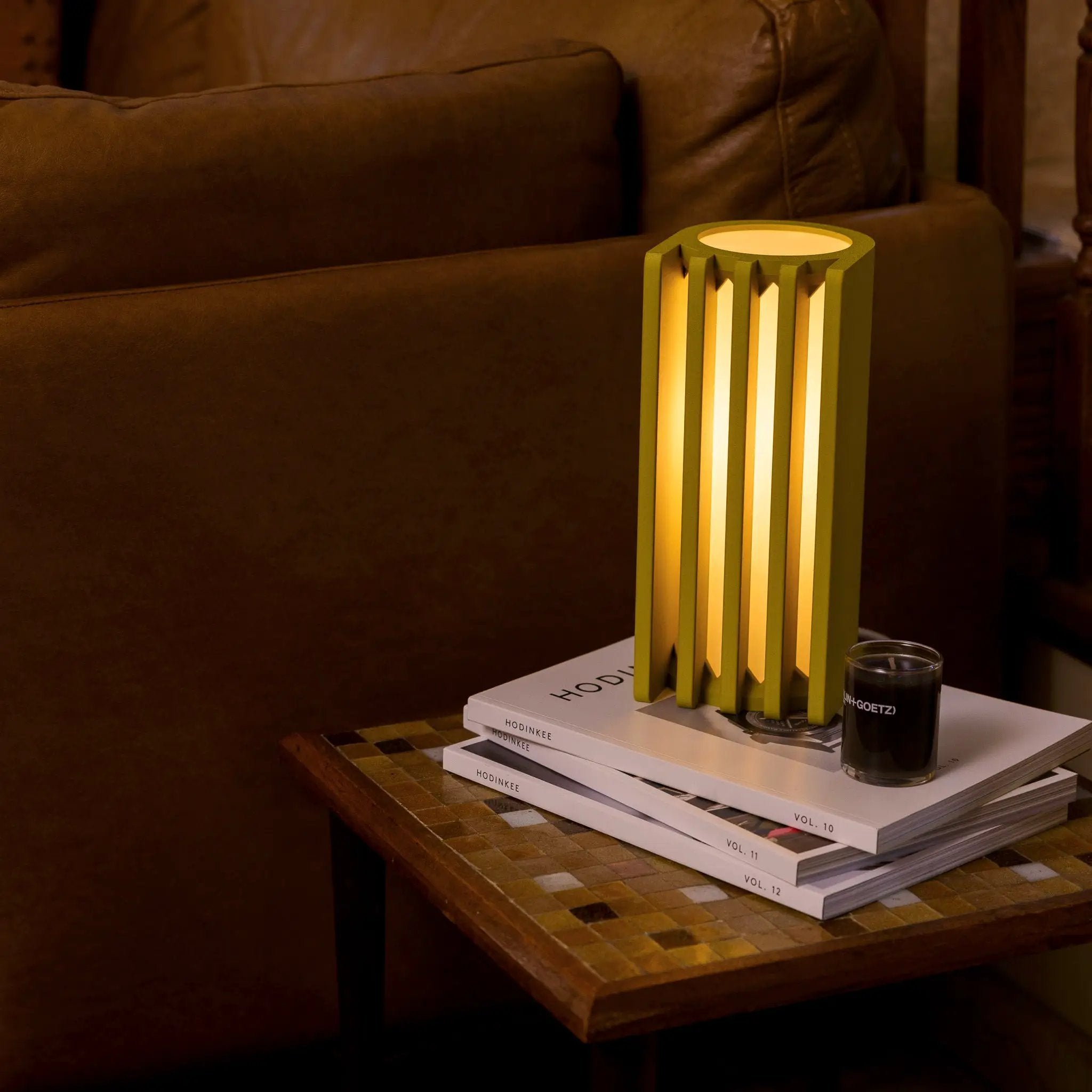 Terra Labs Radiator Table Lamp, lime-green slat design with warm glow on stack of magazines