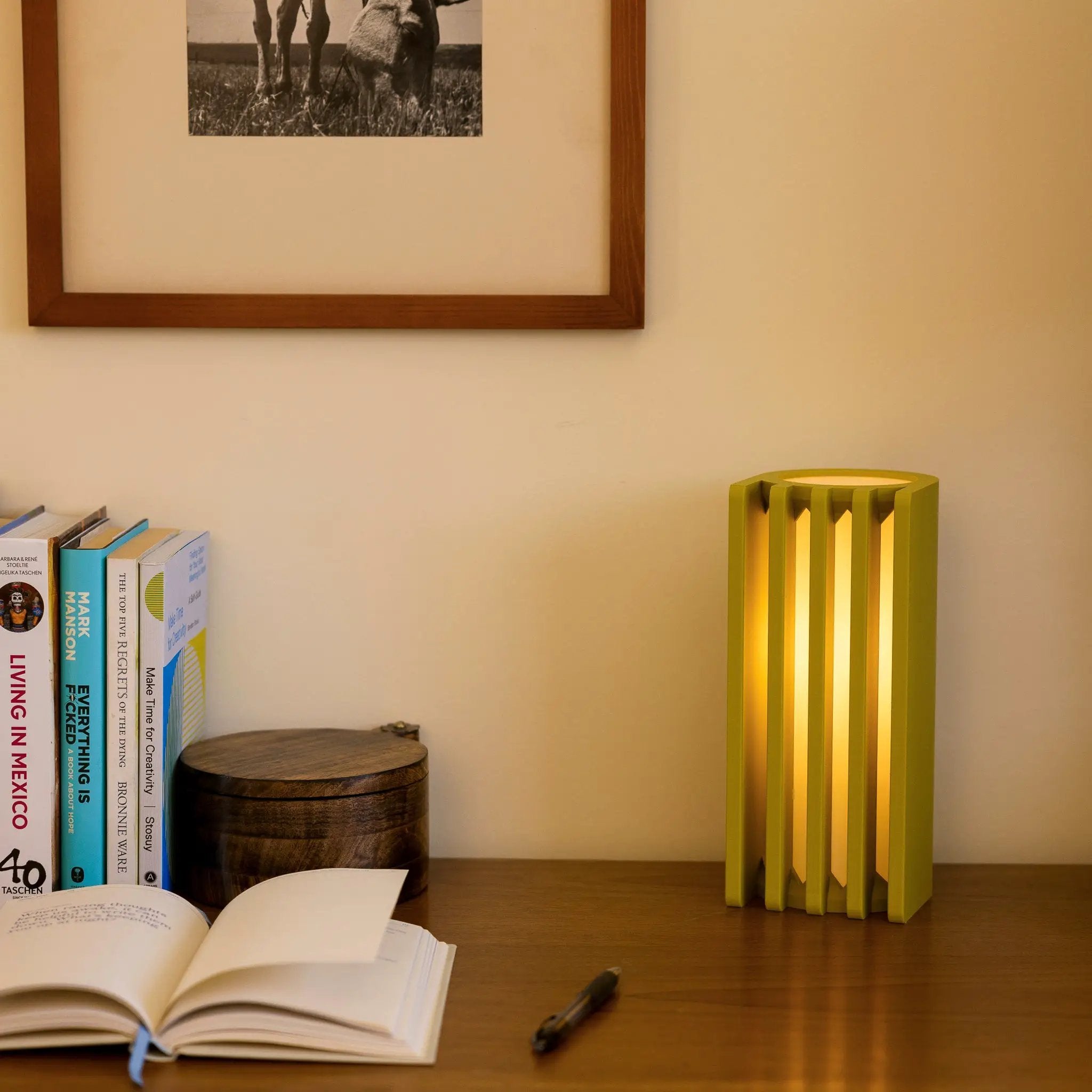 Radiator table lamp by Terra Labs, yellow-green finish, on a wooden desk beside books.