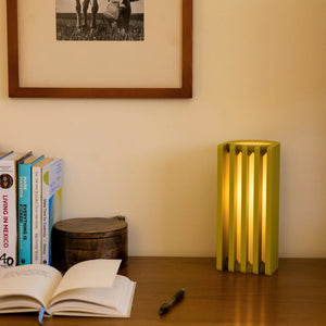 Radiator table lamp by Terra Labs, yellow-green finish, on a wooden desk beside books.