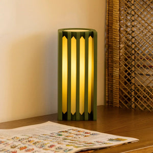 Radiator Table Lamp in green metal frame with vertical slats and warm yellow light.