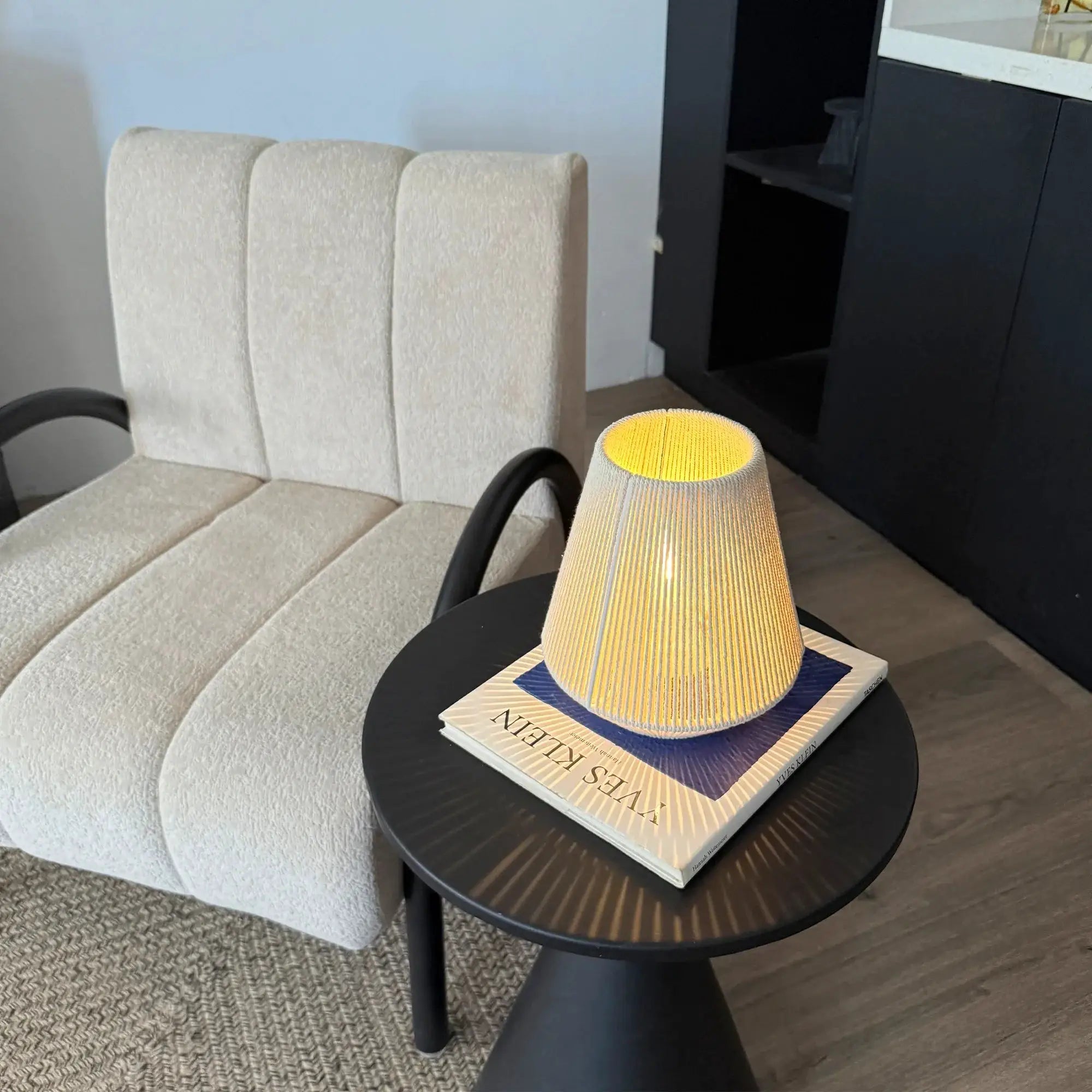 Beige woven table lamps with warm yellow interior on a black round table; set of 2.