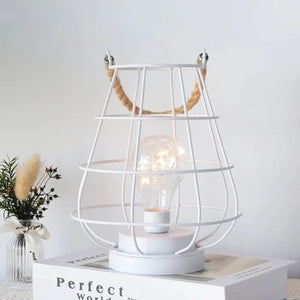 White cordless accent lamp with Edison-style bulb inside a metal cage and rope handle