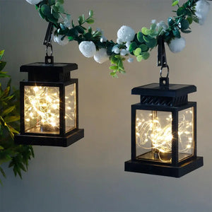 Set of 2 JHY DESIGN Solar Lantern Lights with black metal frames and glass panes, illuminated by warm fairy lights