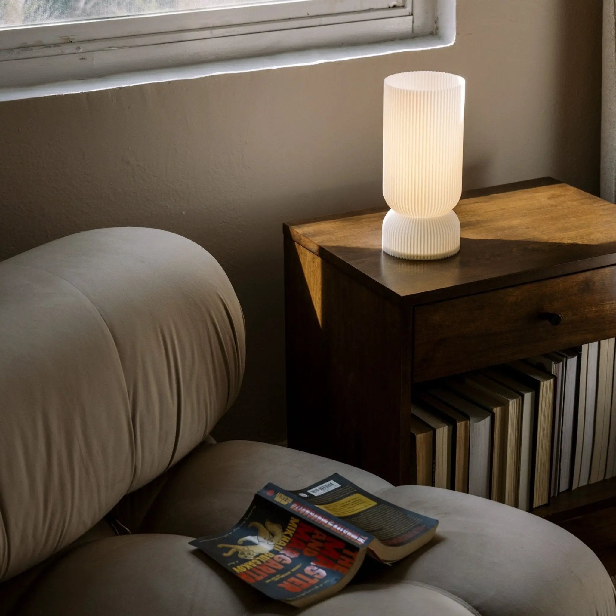 Terra Labs Stance table lamp with ribbed white shade on a dark wood nightstand.