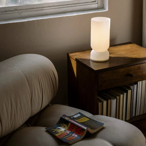 Terra Labs Stance table lamp with ribbed white shade on a dark wood nightstand.