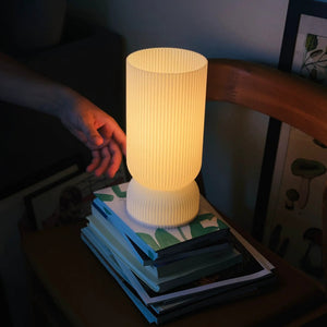 Stance Table Lamp; cream ribbed shade with warm glow on desk