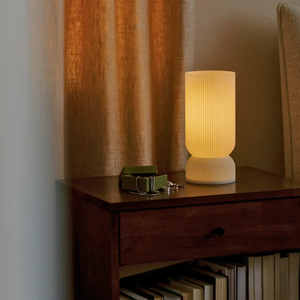Stance Table Lamp by Terra Labs, ribbed cream ceramic with warm glow on wooden console.