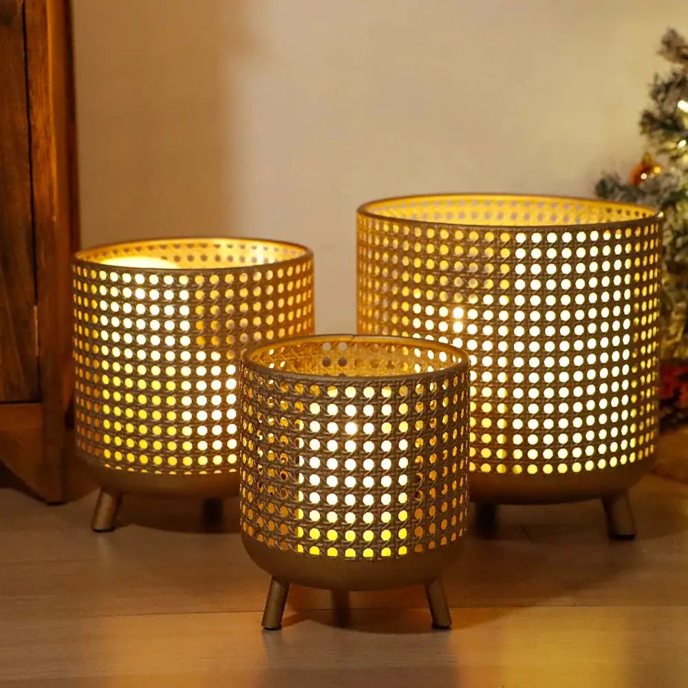 Set of 3 antique gold perforated metal candle holders on short legs, warm glow.